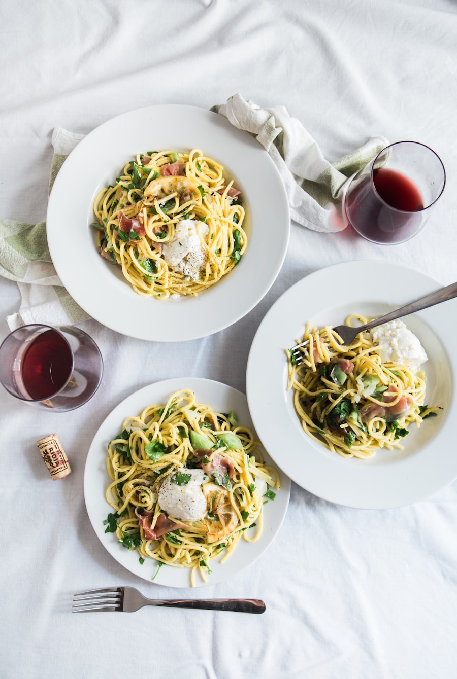 Three plates of pasta with wine glasses